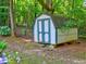 Garden shed with painted white and blue exterior sitting amid lush greenery in wooded backyard at 4512 Woodlawn Lake Dr, Marietta, GA 30068