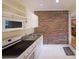 Functional kitchenette featuring white appliances, a brick accent wall, and cabinets for convenient meal prep at 6880 Mark Turner Rd, Lithia Springs, GA 30122