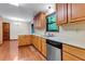 Functional kitchen with wood cabinets, stainless steel dishwasher, and view into the breakfast nook with light fixture at 3442 Winter Wood Trl, Marietta, GA 30062