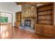 Living room with stone fireplace, built-in shelving, hardwood floors, and view into the dining room with large picture window at 3442 Winter Wood Trl, Marietta, GA 30062