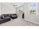 Cozy bonus room with a black leather sectional, modern ceiling fan, and plenty of natural light at 6080 Simone St, Acworth, GA 30101