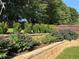 Spacious backyard featuring lush greenery, terraced retaining wall and mature landscaping, enclosed by a wooden fence at 2380 Cain Cir, Dacula, GA 30019