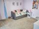 A bright, carpeted bedroom features a single bed with colorful accents and accessories, with a large window letting in natural light at 2380 Cain Cir, Dacula, GA 30019