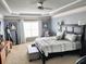Bright main bedroom featuring a spacious bed, neutral carpet, tray ceiling, comfortable seating, and lots of natural light at 2380 Cain Cir, Dacula, GA 30019