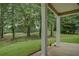 Scenic backyard with covered porch, landscaping, and golf course view beyond the trees at 9187 Plantation Cir, Covington, GA 30014