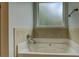 Bathtub with neutral tile surround and obscured glass window for enhanced privacy at 9187 Plantation Cir, Covington, GA 30014