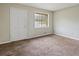 A simple, carpeted bedroom offers neutral tones, a window, and closet for a comfortable and functional space at 1513 Dupree Rd, Woodstock, GA 30189
