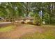 A quaint single-story brick house is nestled among mature trees in a serene landscape, creating a peaceful setting at 1513 Dupree Rd, Woodstock, GA 30189