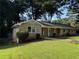Lovely brick home boasts a neatly kept lawn, a covered porch, and lush trees around the property at 2545 Glenrock Dr, Decatur, GA 30032