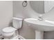 Contemporary powder room features pedestal sink, round mirror, and modern toilet at 801 Tulip Poplar Way # 2501, Lawrenceville, GA 30044