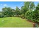 Lush backyard with well-maintained lawn, surrounded by mature trees, providing privacy and a serene outdoor space with a fire pit at 106 April Walk, Mcdonough, GA 30253