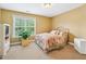 Cozy bedroom featuring a metal-frame bed with floral bedding, a lush houseplant and ample natural light from the large window at 106 April Walk, Mcdonough, GA 30253