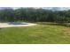 Scenic backyard featuring a pool, pond, and lush green lawn, surrounded by mature trees at 1169 Hodges Cir, Mansfield, GA 30055