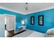 Bright bedroom showcasing blue walls, modern chandelier, artwork, and a stylish writing desk at 1169 Hodges Cir, Mansfield, GA 30055