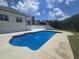 Backyard view of a pool and patio area against a backdrop of lush greenery and a blue sky at 1169 Hodges Cir, Mansfield, GA 30055