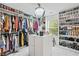 Spacious walk-in closet with custom shelving, center island, and glamorous chandelier lighting at 3246 Spicy Cedar Ln, Lithonia, GA 30038