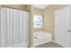 Well-lit bathroom featuring a bathtub with shower, tiled floors, and an exterior window at 401 Buckboard Ln, Locust Grove, GA 30248