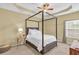 This main bedroom features a canopy bed, tray ceiling, and lots of natural light at 401 Buckboard Ln, Locust Grove, GA 30248