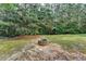 The backyard has an area with a stone fire pit surrounded by grassy areas and many trees at 5965 Vista Brook Dr, Suwanee, GA 30024
