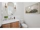 Elegant powder room features a wood cabinet, marble countertop, oval mirror, and decorative sconces at 477 Michael Dr, Alpharetta, GA 30009
