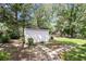 White storage shed in a well-kept backyard with mature trees and a stone walkway at 60 Ivy Dr, Covington, GA 30016