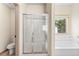Bathroom featuring a tiled floor, glass enclosed shower, large soaking tub, and bright window at 1492 Station Ridge Ct, Lawrenceville, GA 30045