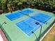 Aerial view of well-maintained blue and green tennis courts with lighting in a wooded setting at 1492 Station Ridge Ct, Lawrenceville, GA 30045