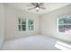 This bedroom features plush carpeting, a ceiling fan, and two windows providing natural light and views of the surrounding landscape at 841 Keystone Dr, Woodstock, GA 30188