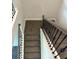 Upward view of a carpeted staircase with dark metal railing and wooden handrail at 3402 Milan Ct, Douglasville, GA 30135