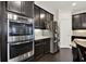 Close-up of the kitchen with stainless steel appliances and dark wood floors and cabinetry at 5640 Hammock Way, Cumming, GA 30028