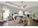 Spacious main bedroom featuring tray ceiling, ceiling fan, hardwood floors, and an adjacent sitting area at 5640 Hammock Way, Cumming, GA 30028