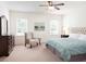 Bright bedroom featuring a tufted headboard, soft linens, and ample natural light from large windows at 2308 Argento Cir, Dacula, GA 30019