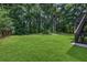 Large, level back yard with lush green grass and mature trees beyond the yard at 397 Lovejoy Cir, Powder Springs, GA 30127