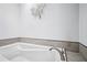 Close-up on a white bathtub with chrome fixtures and tiled trim in a brightly lit bathroom at 5427 Trentham Dr, Atlanta, GA 30338