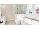 Bright bathroom featuring glass shower, soaking tub, white cabinets and tiling, and gold fixtures at 164 Palm St, Holly Springs, GA 30188