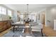 Open-concept living room with wood floors, modern chandelier and open flow to kitchen at 164 Palm St, Holly Springs, GA 30188