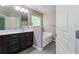 Bright bathroom featuring a dark vanity, tub, and large mirror with modern lighting at 4746 Highland Ave, Sugar Hill, GA 30518