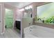 Bright bathroom featuring a white tub, plants in the window, and light gray floors at 4746 Highland Ave, Sugar Hill, GA 30518