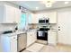 Well-lit kitchen boasts stainless steel appliances, white cabinets, and granite countertops at 430 Thornbush Trce, Lawrenceville, GA 30046