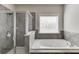 Bathroom featuring a glass-enclosed shower, soaking tub, and grey tiling at 1830 Secretariat Gait Way, Suwanee, GA 30024