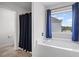 This bathroom features a tub with a shower and blue curtains and an adjacent doorway to a toilet at 230 Waters Edge Pkwy, Temple, GA 30179