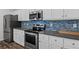 Modern kitchen with stainless steel appliances, white cabinets, gray countertops, and a blue backsplash at 230 Waters Edge Pkwy, Temple, GA 30179