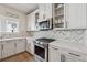 Stylish kitchen with white cabinets, herringbone backsplash, and stainless steel gas range at 1104 Knoxboro Ln, Woodstock, GA 30188