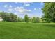 Expansive front yard featuring lush green grass and mature trees set against a blue sky with scattered clouds at 5095 Karr Road Rd, Cumming, GA 30040