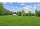 Large front yard featuring green grass and mature trees with a partial view of the house in the background at 5095 Karr Road Rd, Cumming, GA 30040