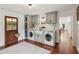 Mudroom laundry area with gray cabinets, white farmhouse sink, and stainless-steel appliances at 5095 Karr Road Rd, Cumming, GA 30040