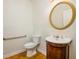 Charming half bathroom featuring hardwood floors, round mirror, and a pedestal sink at 205 Finsbury Park Ct, Suwanee, GA 30024