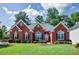 Charming red brick home with a manicured lawn, decorative windows, and lush landscaping at 205 Finsbury Park Ct, Suwanee, GA 30024