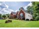 Well-maintained home with a green lawn, red brick exterior, and lush, mature landscaping at 205 Finsbury Park Ct, Suwanee, GA 30024