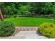 Beautiful backyard featuring a lush lawn, mature trees and stone stairs leading to the yard at 545 Ashvale Overlook, Alpharetta, GA 30005